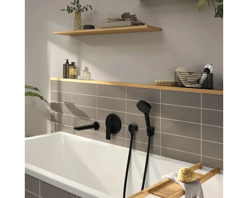 Moderne Badewanne mit mattschwarzen Unterputz-Armaturen, grauen Fliesen und Holzregalen mit Badaccessoires.