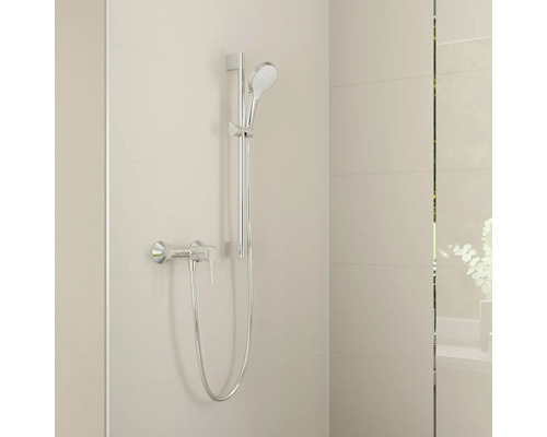 Brauseset in Chrom mit Handbrause, Brausestange, Schlauch und Einhebel-Duscharmatur an einer hell gefliesten Wand.