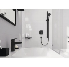 Modernes Badezimmer mit weißem Waschtisch, schwarzer Armatur und schwarzem Duschsystem auf weißen Fliesen.