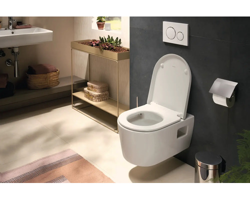Helles, modernes Badezimmer mit Wand-Hängetoilette, Waschbecken, Wandfliesen, Drückerplatte und einem Metall-Pflanzenständer.
