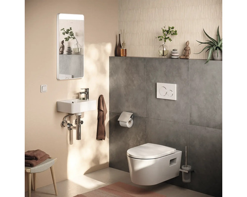 Modernes Gäste-WC mit wandhängendem WC, kleinem Waschbecken, Spiegel mit Beleuchtung und Wandfliesen in Betonoptik.