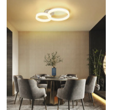 Moderne LED-Deckenleuchte mit zwei Ringen in einem hellen Esszimmer mit rundem Tisch und gepolsterten Stühlen.