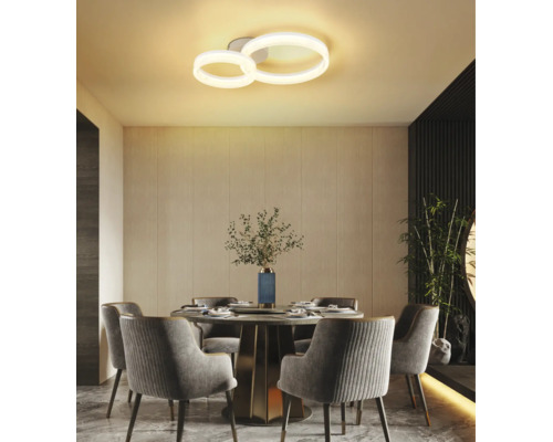 Moderne LED-Deckenleuchte mit zwei Ringen in einem hellen Esszimmer mit rundem Tisch und gepolsterten Stühlen.
