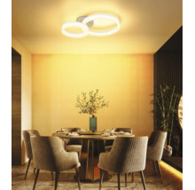 Moderne LED-Deckenleuchte mit zwei Ringen über einem runden Esstisch in einem warm beleuchteten, stilvollen Esszimmer.