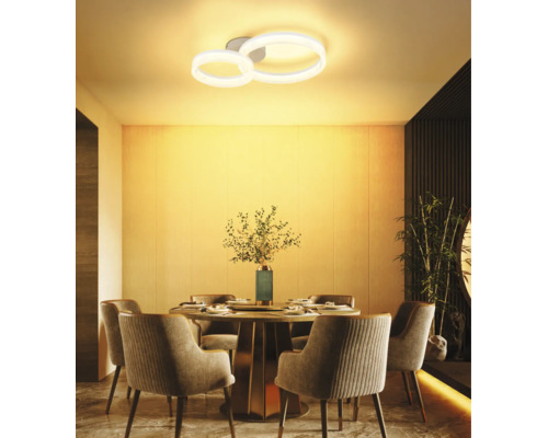 Moderne LED-Deckenleuchte mit zwei Ringen über einem runden Esstisch in einem warm beleuchteten, stilvollen Esszimmer.