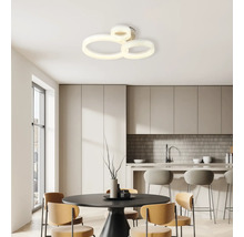 Moderne LED-Deckenleuchte mit drei ineinandergreifenden Ringen in einer hellen, minimalistischen Wohnküche mit Esstisch und Barhockern.