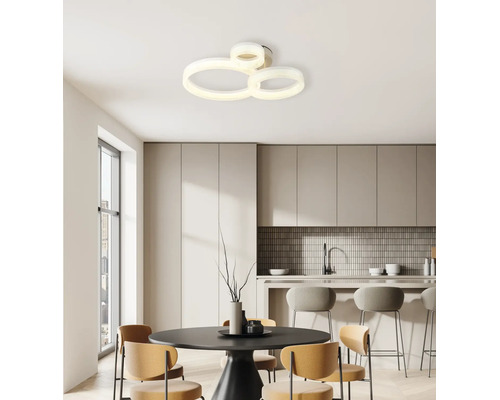 Moderne LED-Deckenleuchte mit drei ineinandergreifenden Ringen in einer hellen, minimalistischen Wohnküche mit Esstisch und Barhockern.