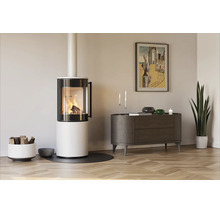 Moderner, weißer Kaminofen mit brennendem Holzfeuer in einem hellen Wohnzimmer mit Parkettboden, Sideboard und einer Zimmerpflanze.