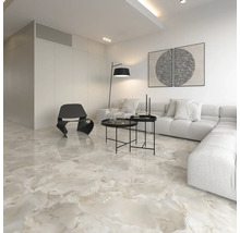Modernes Wohnzimmer mit polierten Bodenfliesen in Marmoroptik, weißem Ecksofa, schwarzen Beistelltischen und einem modernen Sessel.