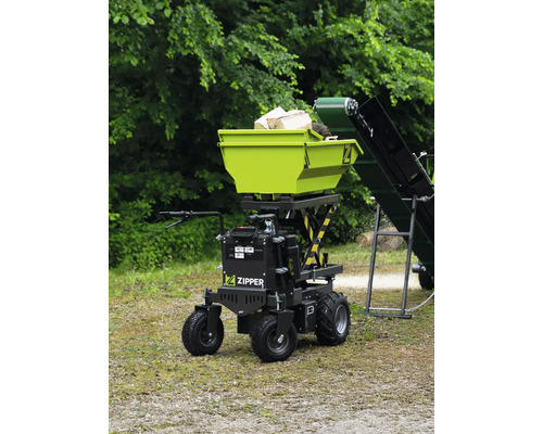Zipper Elektro-Minidumper mit Scherenhub-Funktion und beladener Mulde neben einem Förderband im Außenbereich.