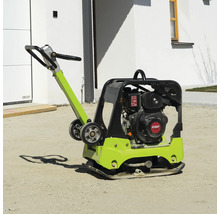 Rüttelplatte mit KOOP-Motor auf sandigem Boden vor einem Haus.