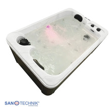 Rechteckiger Whirlpool mit sprudelndem Wasser, rosa LED-Licht, Kopfstützen, dunkler Verkleidung und Sanotechnik International Logo.