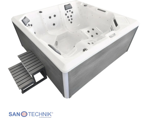 Quadratischer Außenwhirlpool mit Massagedüsen, Kopfstützen und grauer Treppe. Weiße Wanne und graue Verkleidung in Holzoptik.