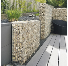 Gabionenwand aus Metallkörben mit hellen Steinen auf einer Terrasse mit grauen Dielen und Sichtschutzelementen im Garten.