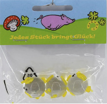 Drei kleine Glasmurmeln mit gelben Verzierungen in einer Verkaufspackung mit der Aufschrift Jedes Stück bringt Glück