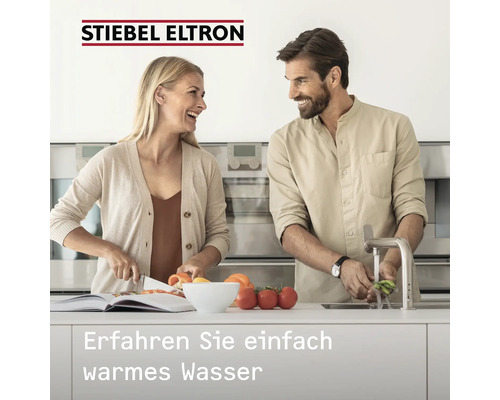 Stiebel Eltron Logo. Paar in heller, moderner Küche beim Gemüsewaschen und Schneiden. Text: Erfahren Sie einfach warmes Wasser.