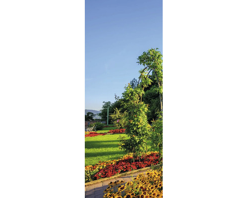 Gepflegter Garten mit buntem Blumenbeet, grünem Rasen und einer Kletterpflanze an einem Rosenbogen unter blauem Himmel.