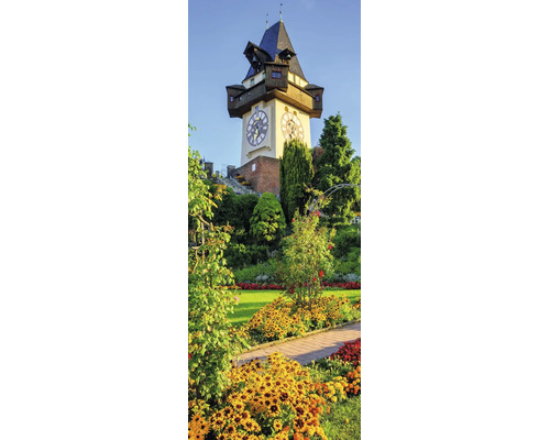 Grazer Uhrturm am Schlossberg in einer Parkanlage mit Blumenbeeten und Bäumen.