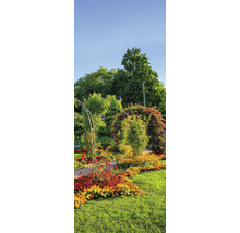 Hell gestalteter Garten mit einem Metall-Rosenbogen über einem Weg, bunten Blumenbeeten und hohen Bäumen.