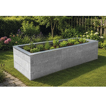 Hochbeet aus Steinblöcken mit Metallabschlusskante im Garten, bepflanzt mit Kräutern und Salat.
