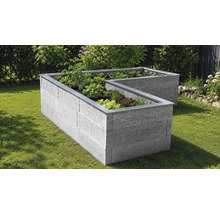 L-förmiges Hochbeet aus Betonsteinen in Granitoptik mit Metallrand, bepflanzt mit Kräutern und Salat auf einer Rasenfläche im Garten.