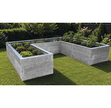 U-förmiges Hochbeet aus grauen Mauersteinen mit Metallabschluss, bepflanzt mit Salat und Tomaten in einem Garten auf einer Rasenfläche.