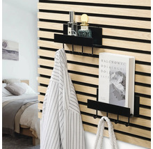 Schwarze Metallregale mit Haken an einer Wand aus Holzlamellen in einem modern eingerichteten Schlafzimmer mit Buch, Flaschen und Kleidung.