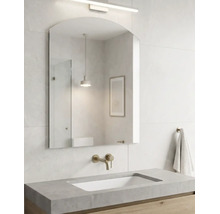 Helles, modernes Badezimmer mit gewölbtem Wandspiegel, Wandarmatur in Messingoptik, Waschtisch in Betonoptik und einem Unterschrank aus Holz.