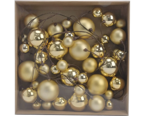 Goldene Weihnachtskugeln in verschiedenen Größen, glänzend und matt, an braunen Zweigen in einer Schachtel.