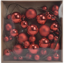 Set aus roten Weihnachtskugeln in verschiedenen Größen mit glänzender und matter Oberfläche an Dekozweigen in einer Schachtel