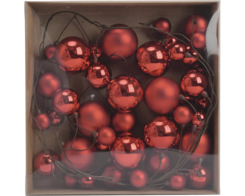 Set aus roten Weihnachtskugeln in verschiedenen Größen mit glänzender und matter Oberfläche an Dekozweigen in einer Schachtel