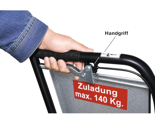 Hand am Handgriff einer Transportkarre mit Bremshebel und einem Schild für die maximale Zuladung von 140 Kilogramm.
