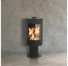 Moderner Kaminofen auf einem Standfuß mit brennendem Feuer hinter einer Glasscheibe vor einer Wand in Betonoptik.