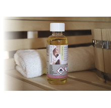 Saunaduft Lemongras 250 Milliliter in einer Flasche auf einer Holzbank in einer Sauna neben einem Handtuch und einem Saunakübel.