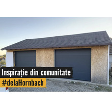 Doppelgarage im Bau mit OSB-Plattenwänden, zwei anthrazitfarbenen Sektionaltoren und einem dunklen Schindeldach.