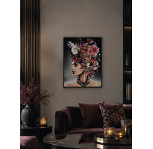 Wohnzimmer mit beleuchtetem Wandbild einer Frau mit Blumenkopfschmuck, dunklem Samtsofa und stimmungsvoller Beleuchtung durch Kerzen.