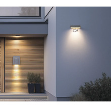 Moderne Außenwandleuchte und Solar-Hausnummernleuchte LED an einem Hauseingang mit Holzfassade und verputzter Wand.