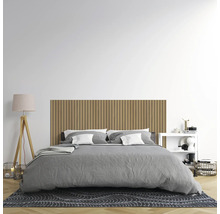 Modernes Schlafzimmer mit einem Wandpaneel aus Holzlamellen als Kopfteil, einem Bett mit grauer Bettwäsche und einer Stehleuchte auf Holzfuß.