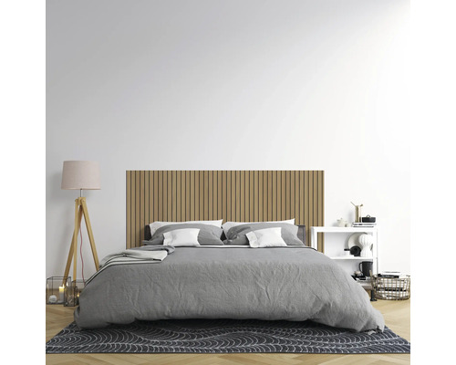 Modernes Schlafzimmer mit einem Wandpaneel aus Holzlamellen als Kopfteil, einem Bett mit grauer Bettwäsche und einer Stehleuchte auf Holzfuß.