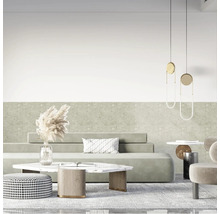 Modernes Wohnzimmer mit hellgrüner Wand in Steinoptik, minimalistischem Sofa, Marmortisch, gemustertem Pouf und hängenden Designerleuchten.