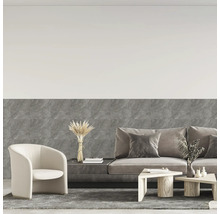Modernes Wohnzimmer mit grauen Wandfliesen in Marmoroptik, Stoffsofa, hellem Sessel und Holztischen.