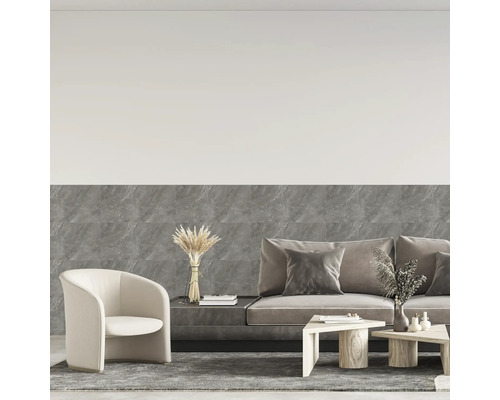 Modernes Wohnzimmer mit grauen Wandfliesen in Marmoroptik, Stoffsofa, hellem Sessel und Holztischen.