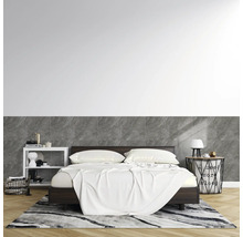 Modernes Schlafzimmer mit dunklem Holzbett. Die Wand ist halbhoch mit Fliesen in Marmoroptik verkleidet. Heller Parkettboden und gemusterter Teppich.