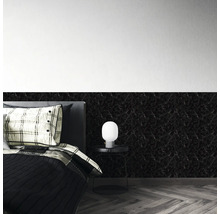 Schwarze Wandpaneele in Marmoroptik an einer Schlafzimmerwand hinter einem Bett mit Beistelltisch und Lampe.