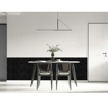 Modern eingerichteter Essbereich mit einem Esstisch vor einer Wand mit schwarzen Wandpaneelen in Marmoroptik im unteren Bereich.