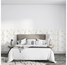 Schlafzimmer mit Vliestapete in Marmoroptik mit goldenen Adern, grauem Polsterbett, weißer Bettwäsche und Boden in Fischgrätoptik.