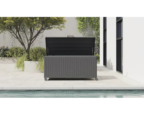 Geöffnete Garten-Auflagenbox mit Rollen auf einer gefliesten Terrasse am Pool. Die Metallbox hat eine gerippte Front und Gasdruckfedern am Deckel.