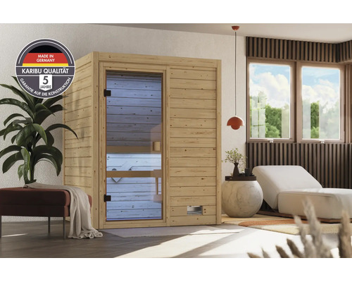 Karibu Elementsauna aus Holz in einem modernen Wohnraum mit Glasfront und Siegel für deutsche Qualität sowie fünf Jahre Garantie auf Konstruktion.