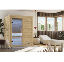Moderne Elementsauna aus naturbelassenem Holz mit Glastür in einem hellen, wohnlich eingerichteten Wellnessbereich mit Liege und Pflanzen.