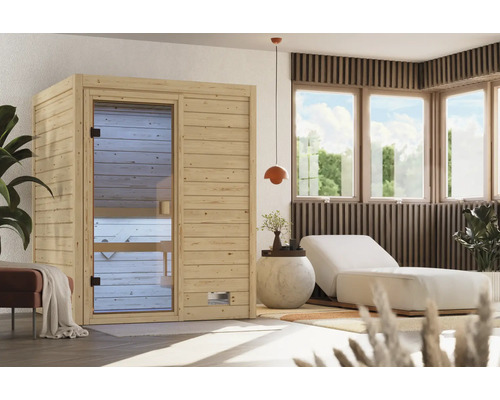 Moderne Elementsauna aus naturbelassenem Holz mit Glastür in einem hellen, wohnlich eingerichteten Wellnessbereich mit Liege und Pflanzen.